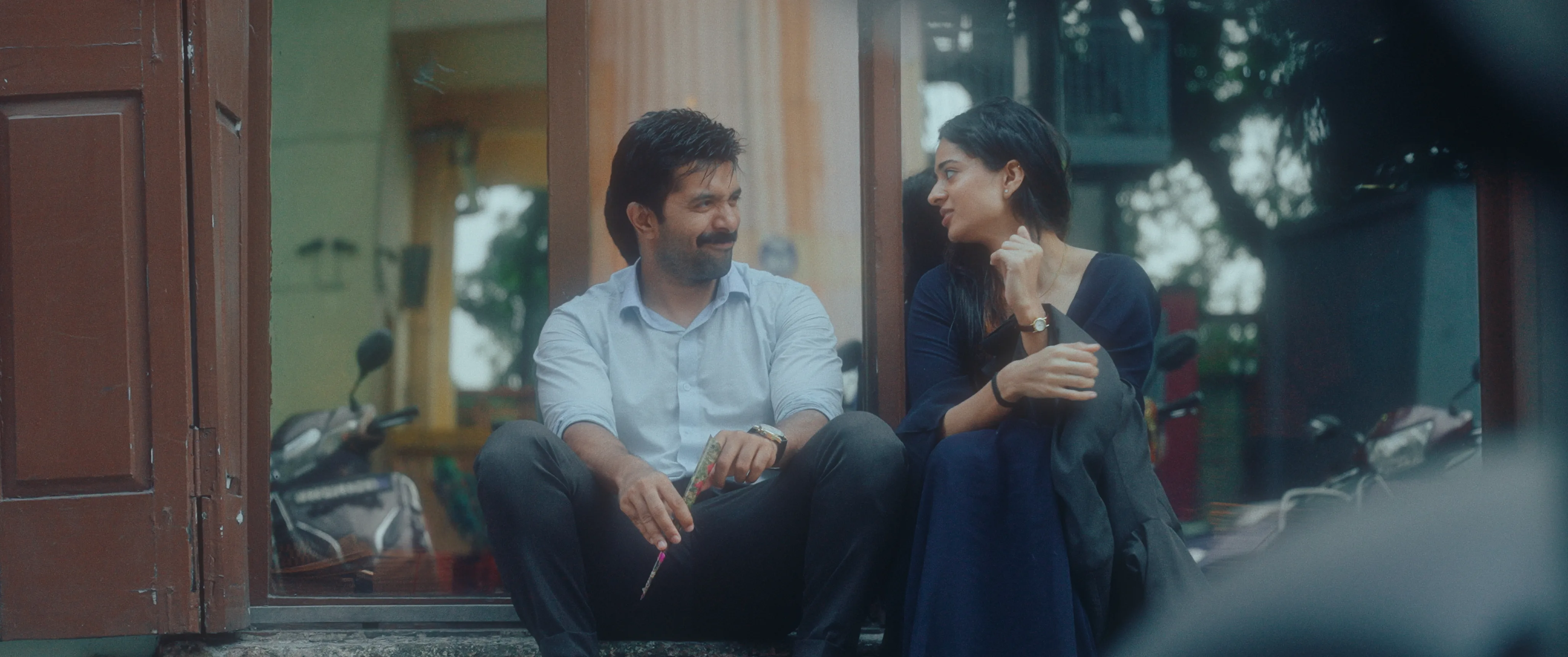 Man and woman sitting on a doorstep and smiling at each other.