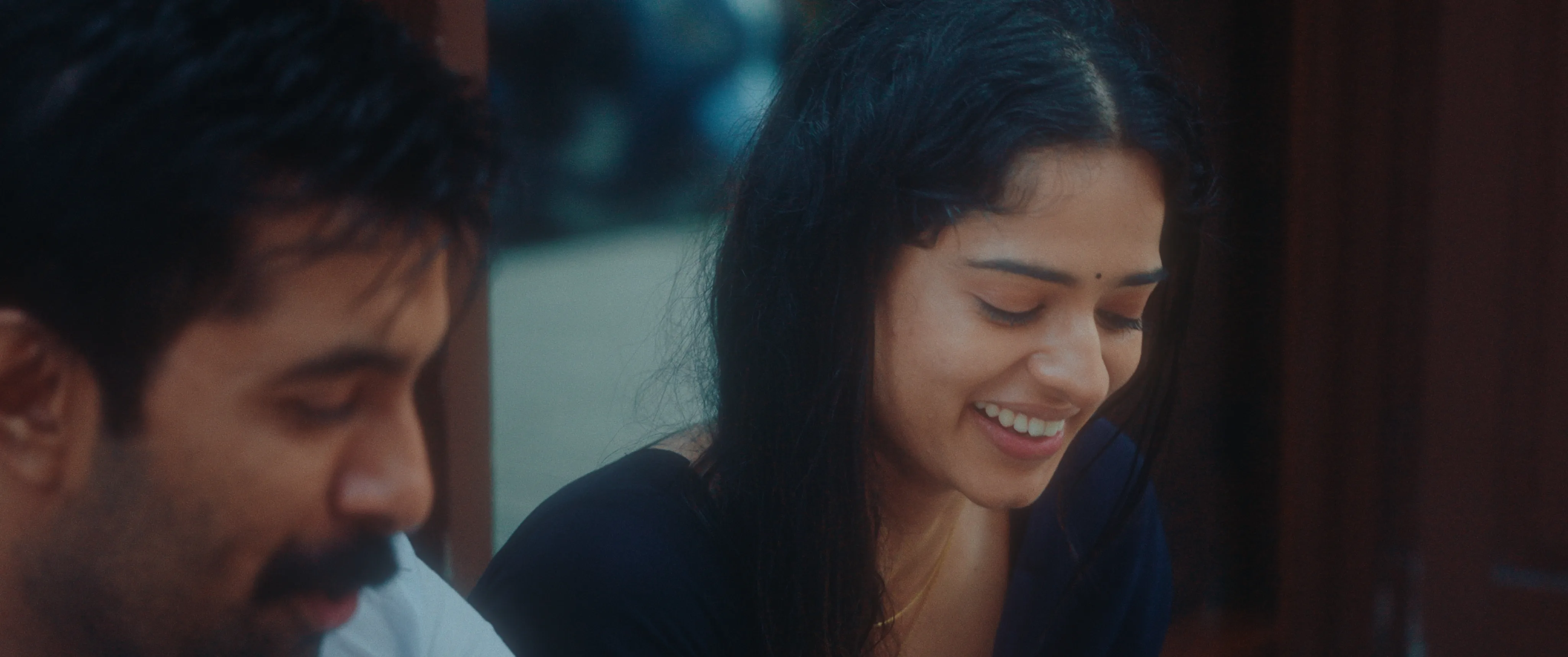 Woman smiling while seated beside a man outdoors.