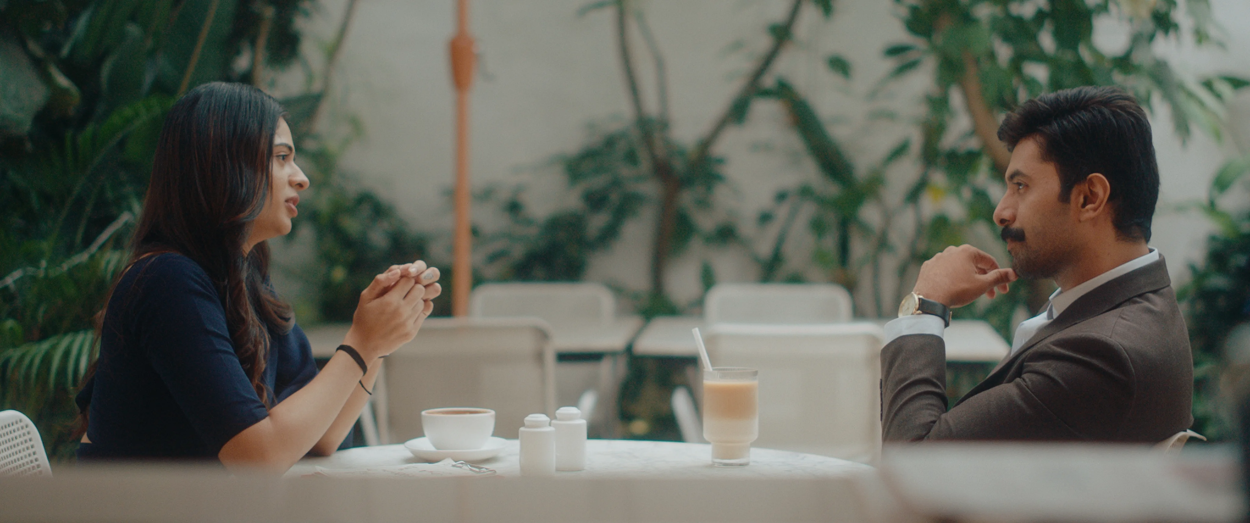 Woman and man seated across from each other at an outdoor café during the day.